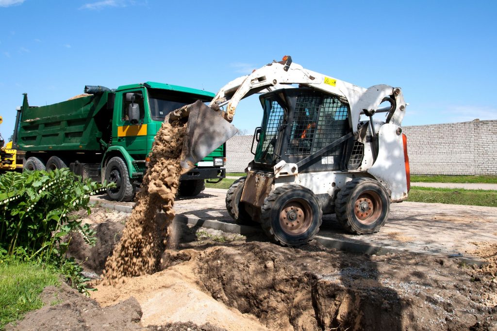 Crew member on a job site pouring materials and clearing land