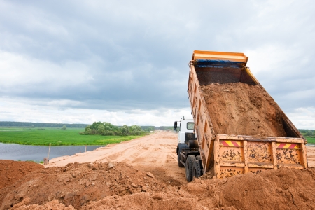 Excavating truck offloading dirt from a project site